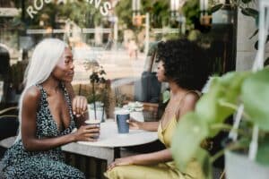 2 women talking outside at a table
